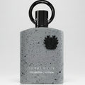 Perfume bottle with speckled gray design and black cap on a white background